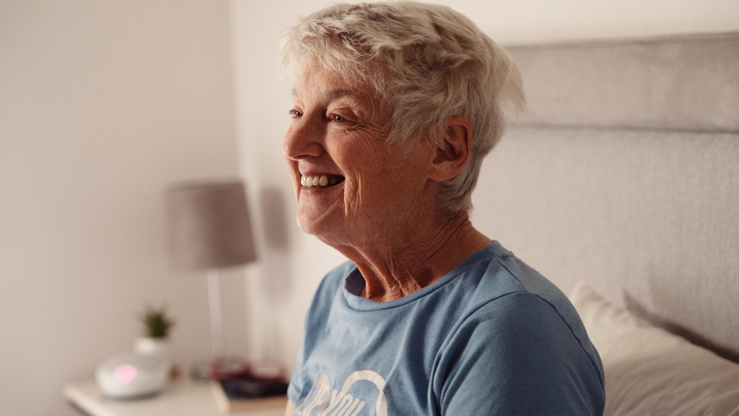 An older woman smiling in her bedroom