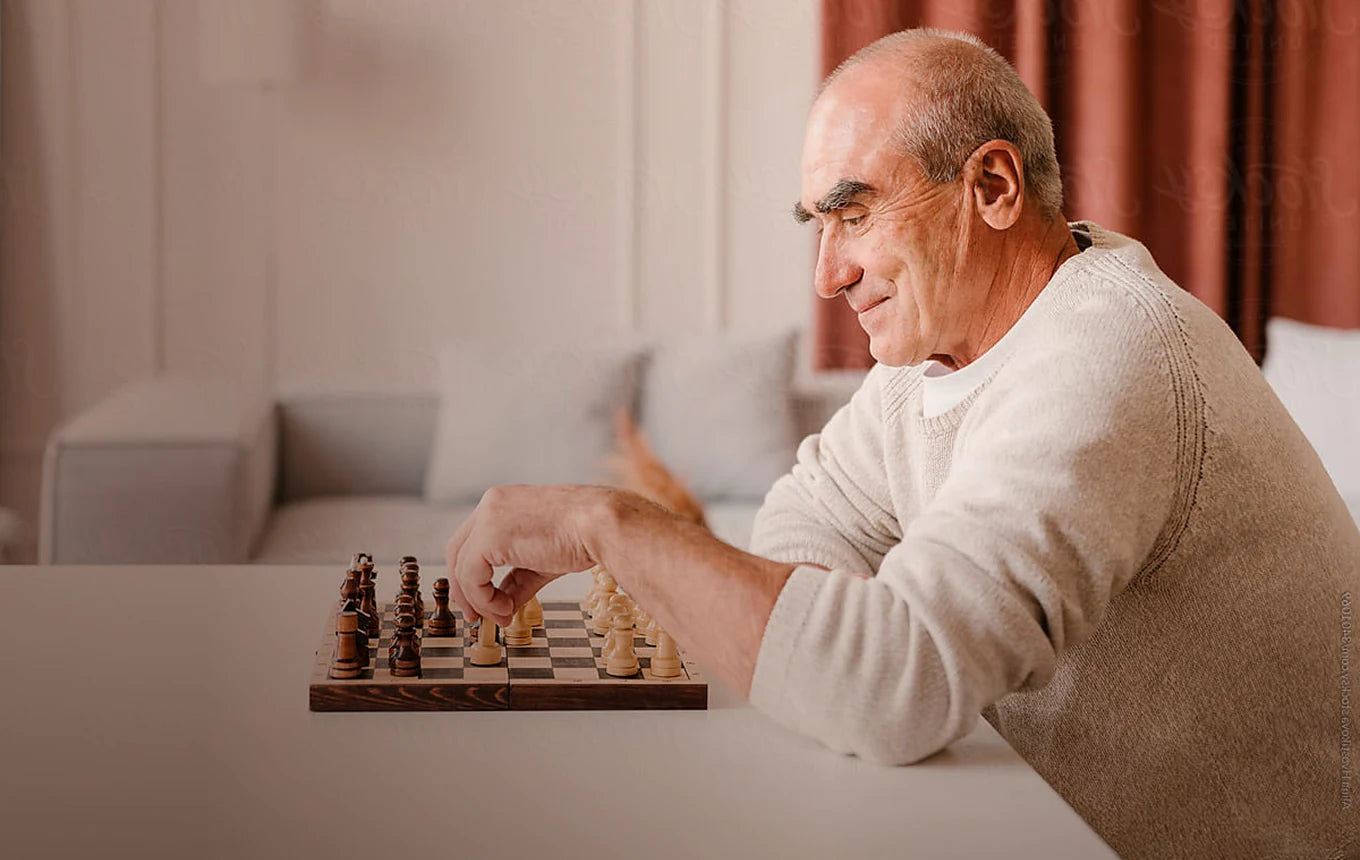An older man playing chess at home